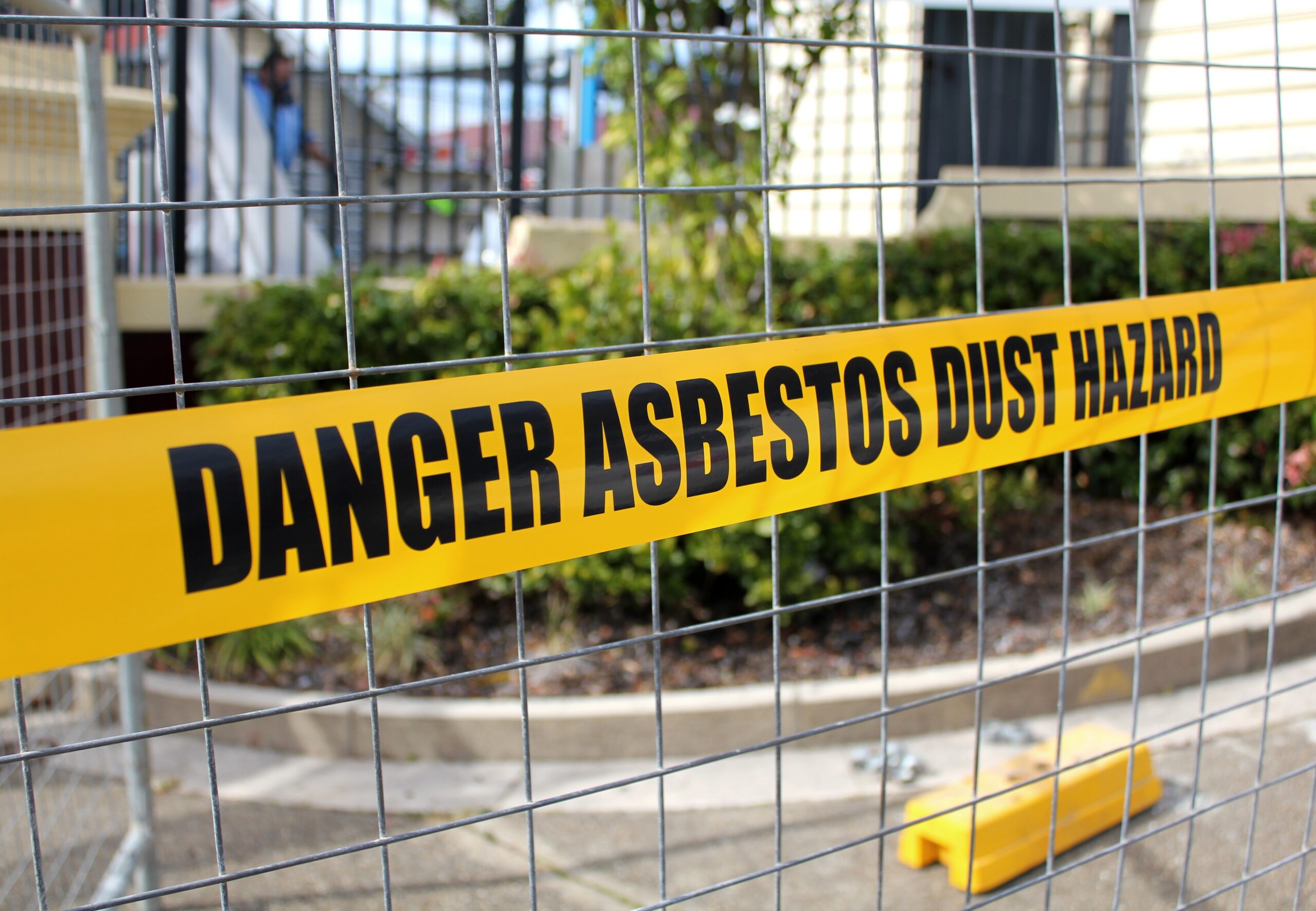 yellow caution tape warning 'danger asbestos dust hazard'